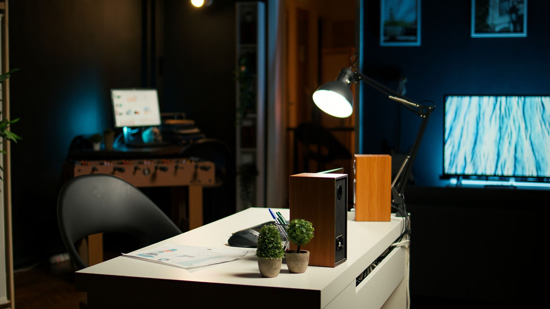 A desk with a lamp and a speaker on it in a dark room.