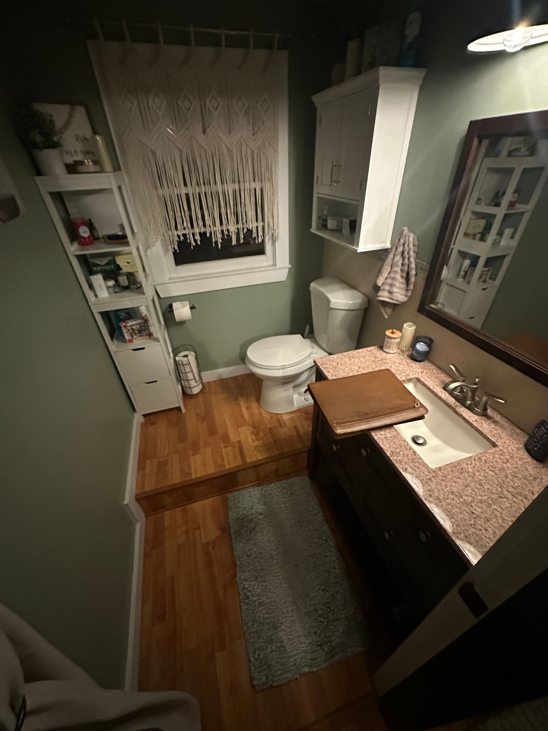 A bathroom with a toilet , sink , mirror and window.
