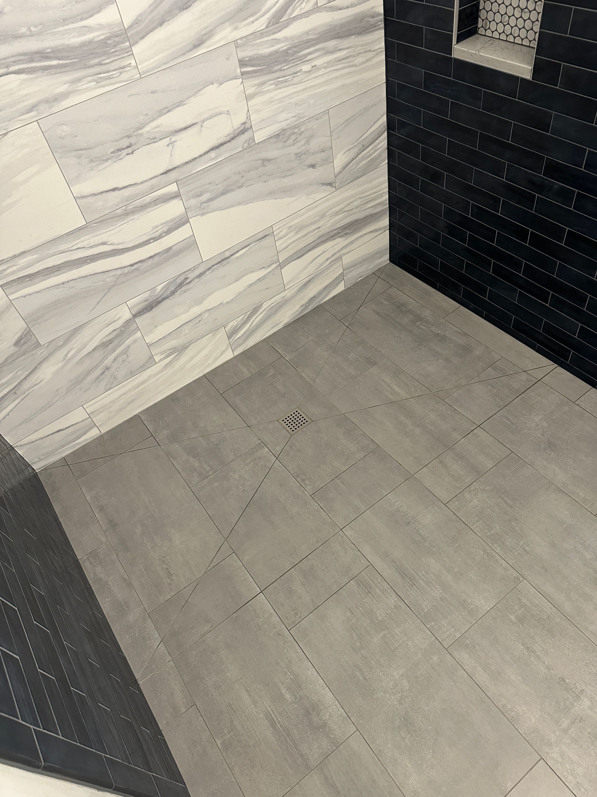 A bathroom with black and white tiles and a walk in shower.