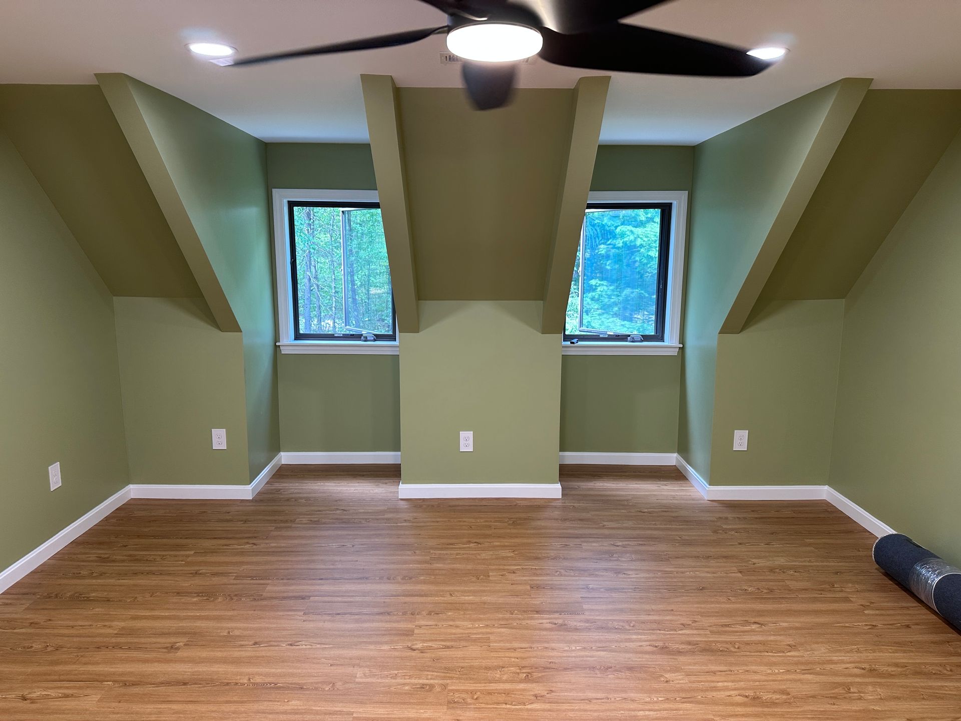 An empty room with green walls and a ceiling fan.