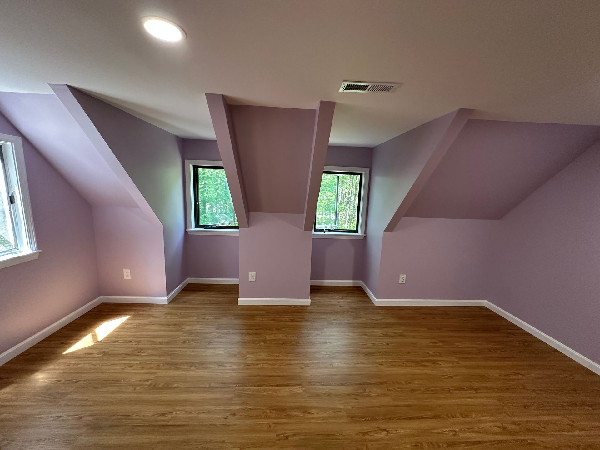 An empty room with purple walls and hardwood floors.
