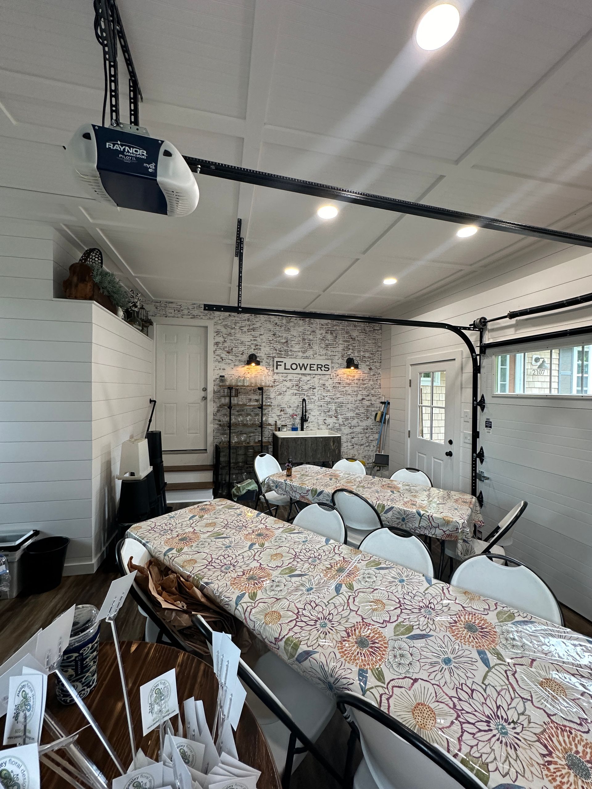 A large room with tables and chairs and a garage door open.