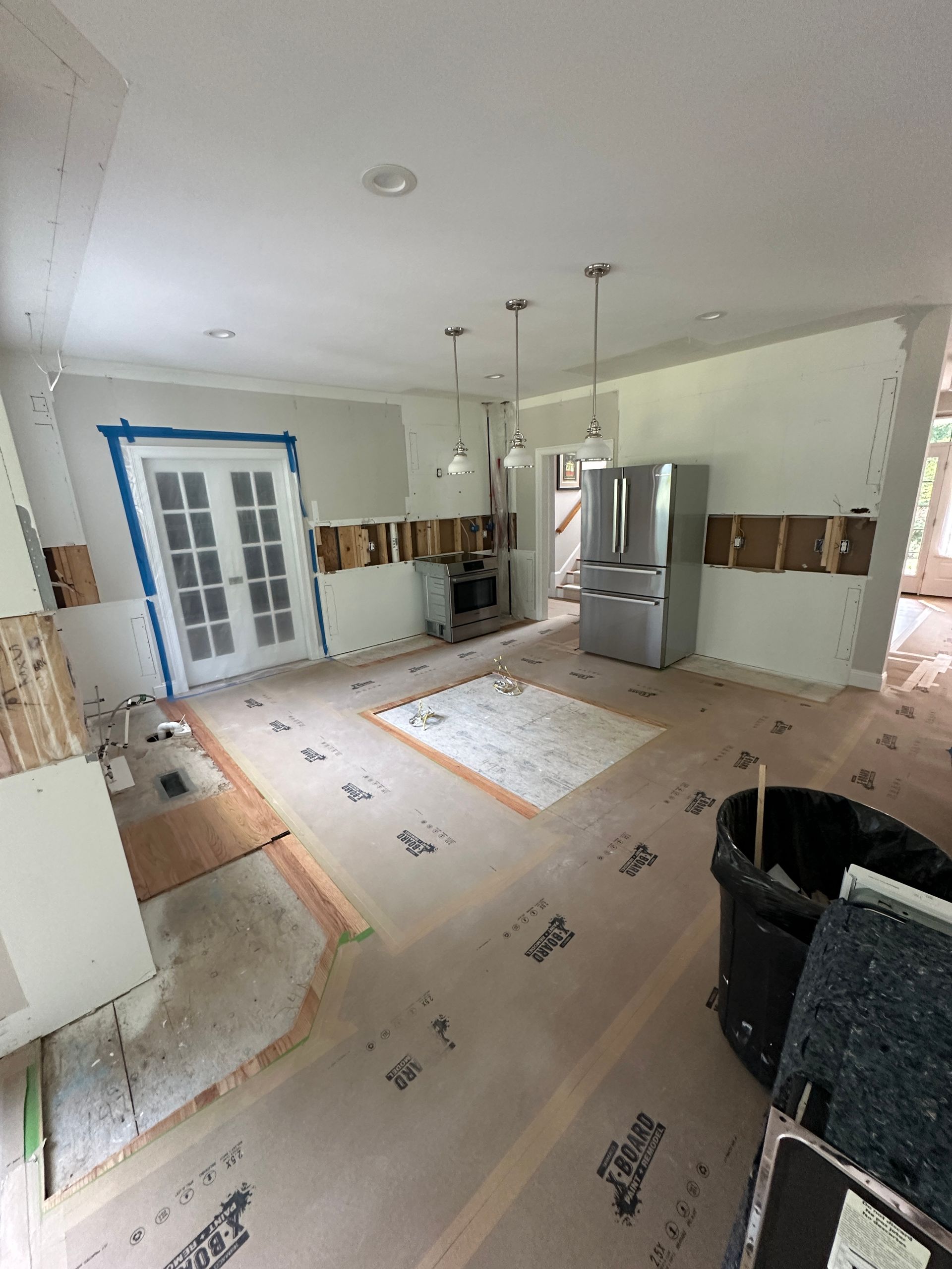 A kitchen under construction with a stainless steel refrigerator.