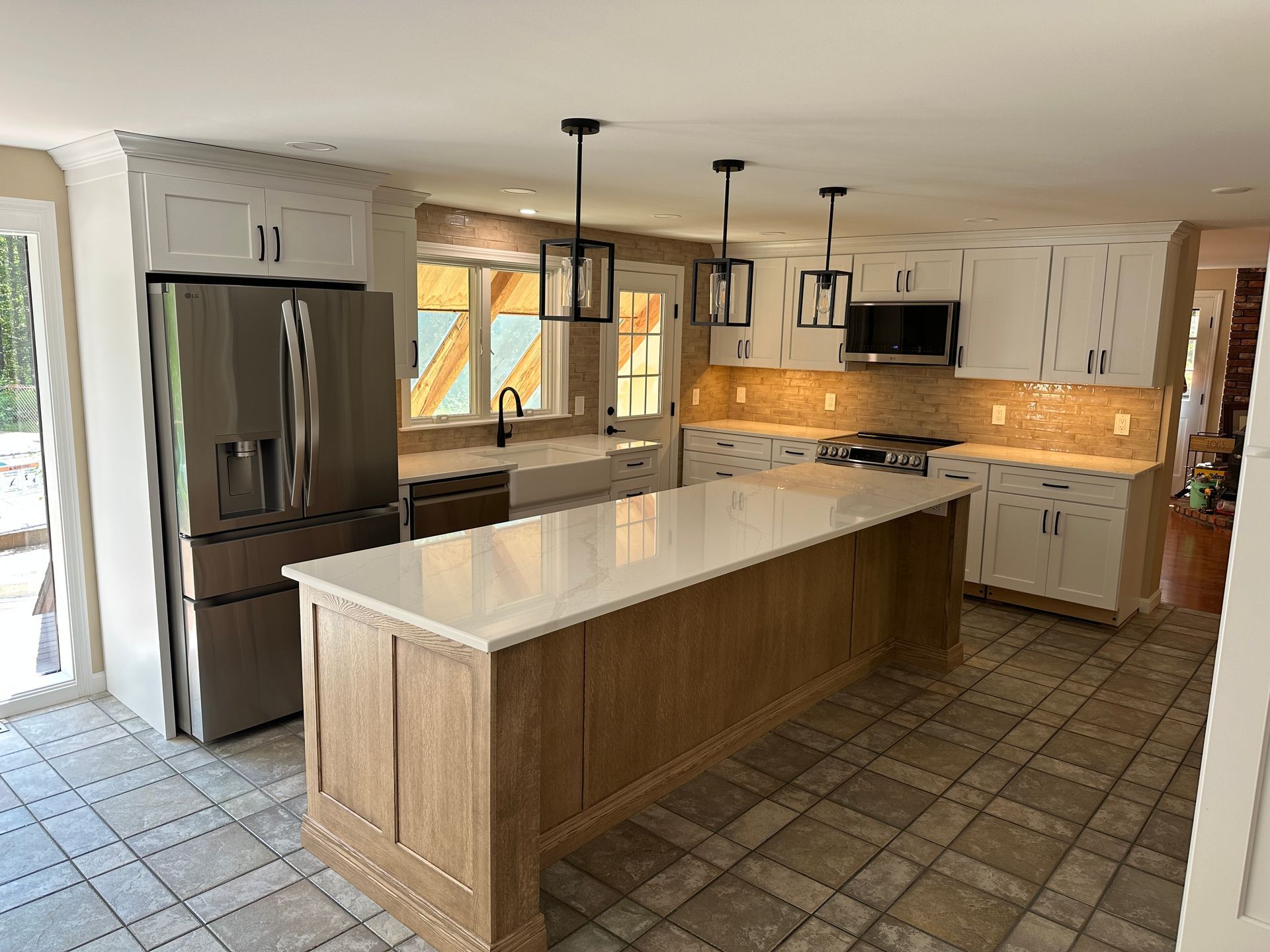 A kitchen with white cabinets , stainless steel appliances , and a large island.