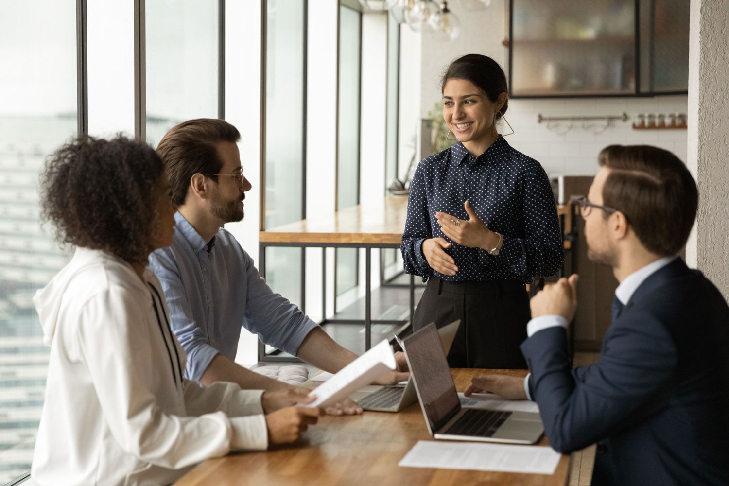 woman leading meeting with diverse colleagues, discussing project strategy
