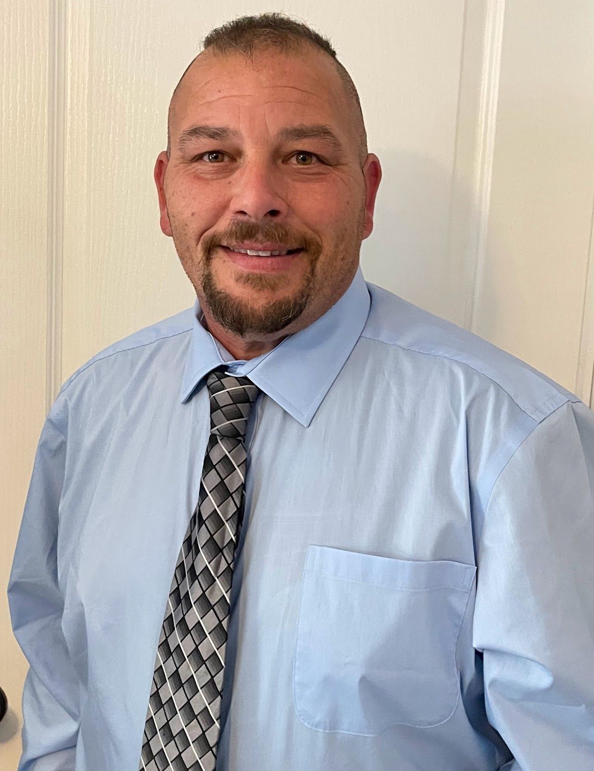 A man in a suit shakes hands with another man in a blue shirt