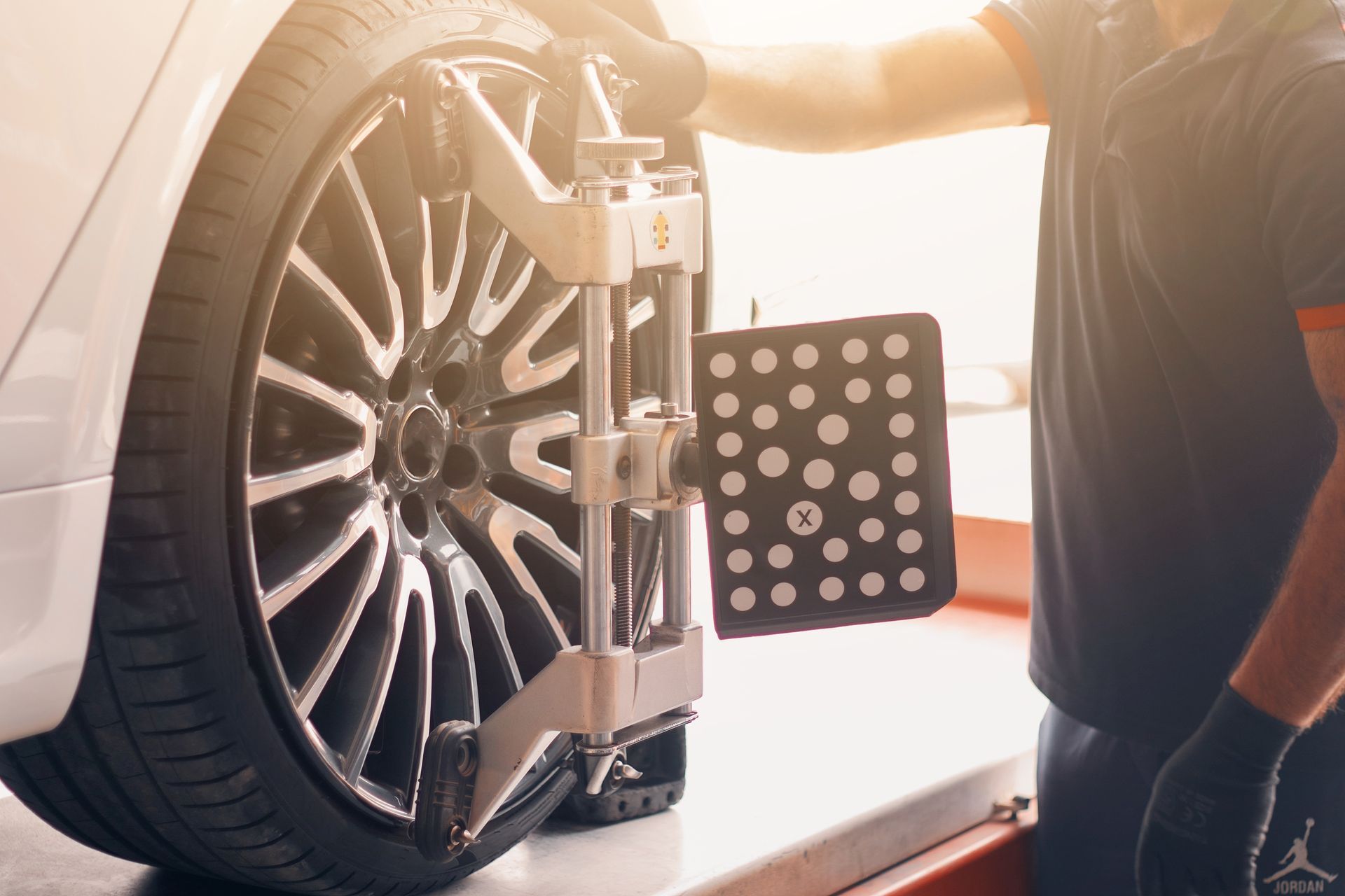 Hands in work gloves hold up a car exhaust pipe while working under a vehicle.