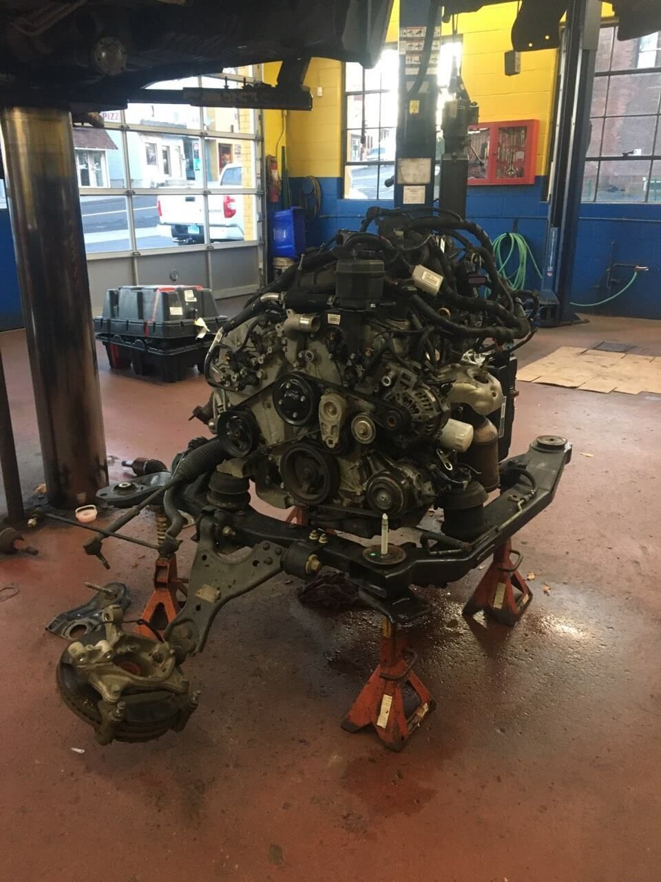 Engine and front suspension on jack stands in a car repair shop.