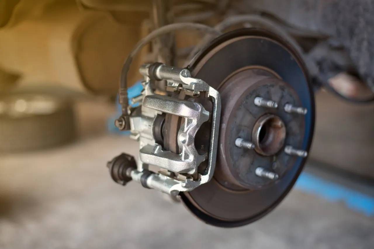 Close-up of a car's brake assembly, showing the rotor, caliper, and lug studs.