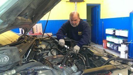 Mechanic working on a car engine in a garage.