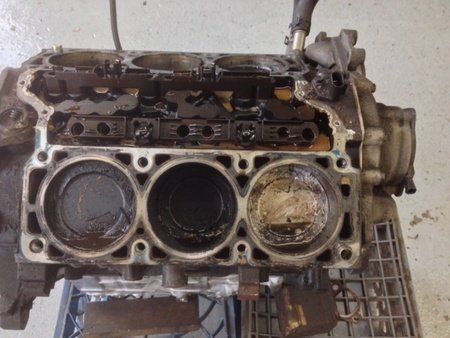 Engine block with three visible cylinders, covered in oil.