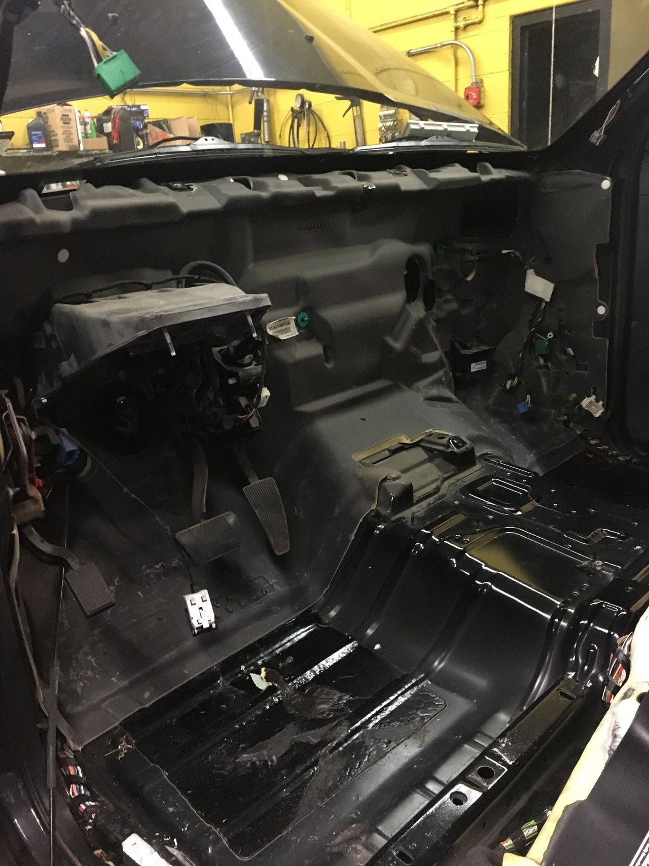 Interior car cabin disassembled, showing dashboard removed, revealing wiring and floor.