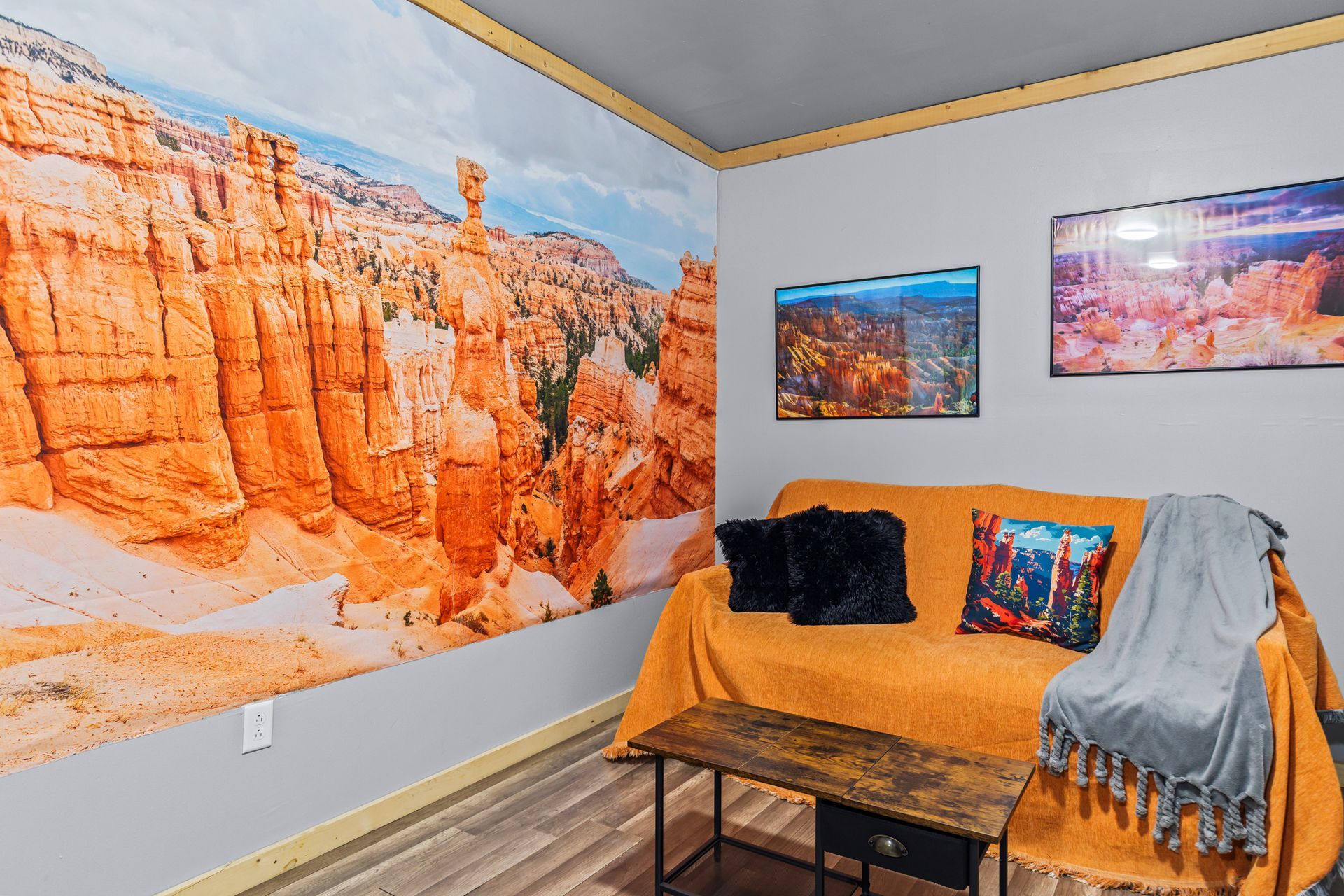 Cozy room with orange couch, landscape mural, and framed art.