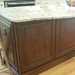 A Kitchen Island with A Granite Counter Top and Wooden Cabinets.