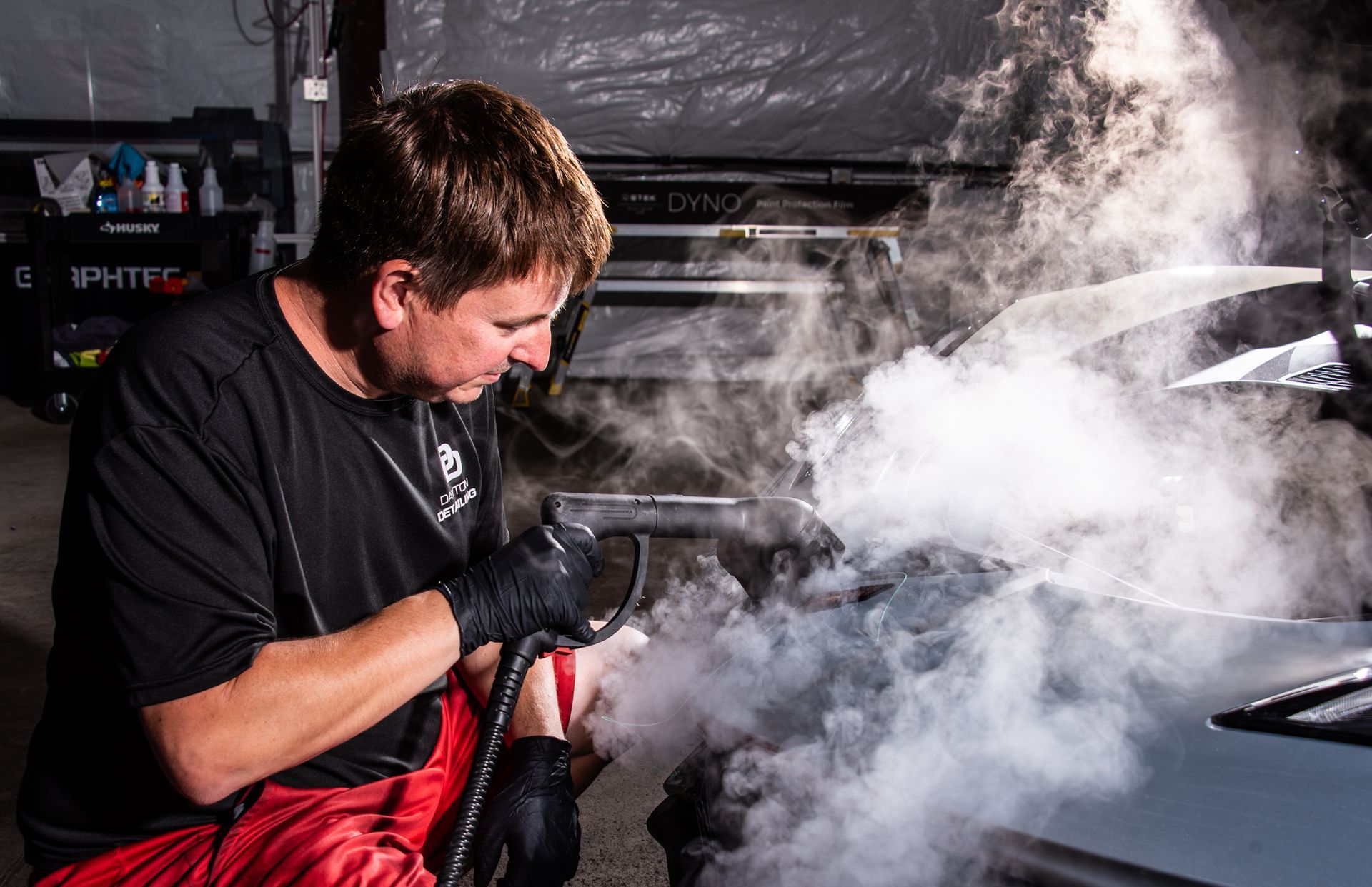 A silver corvette is parked in front of a building.