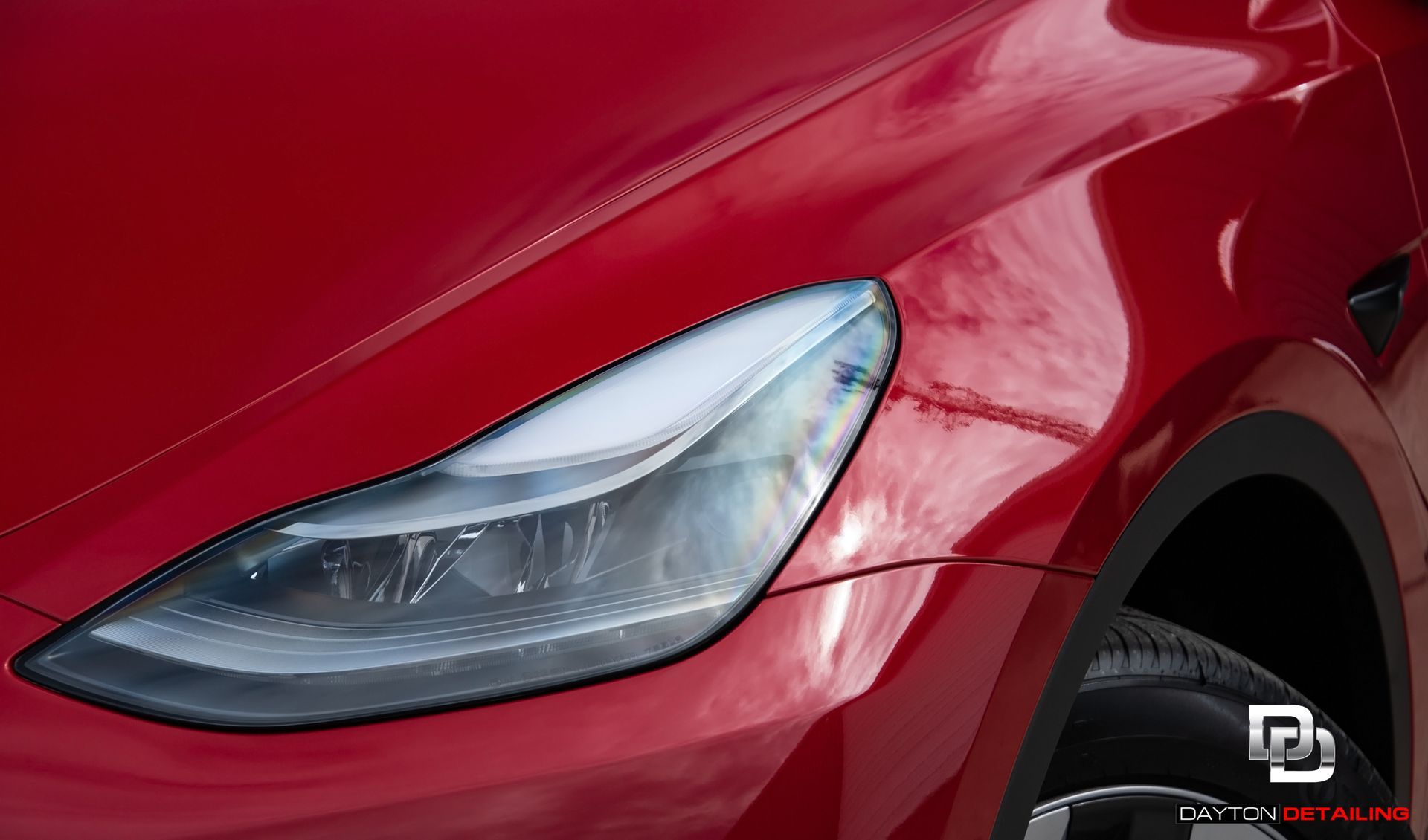 Red Tesla car headlight and front quarter panel.