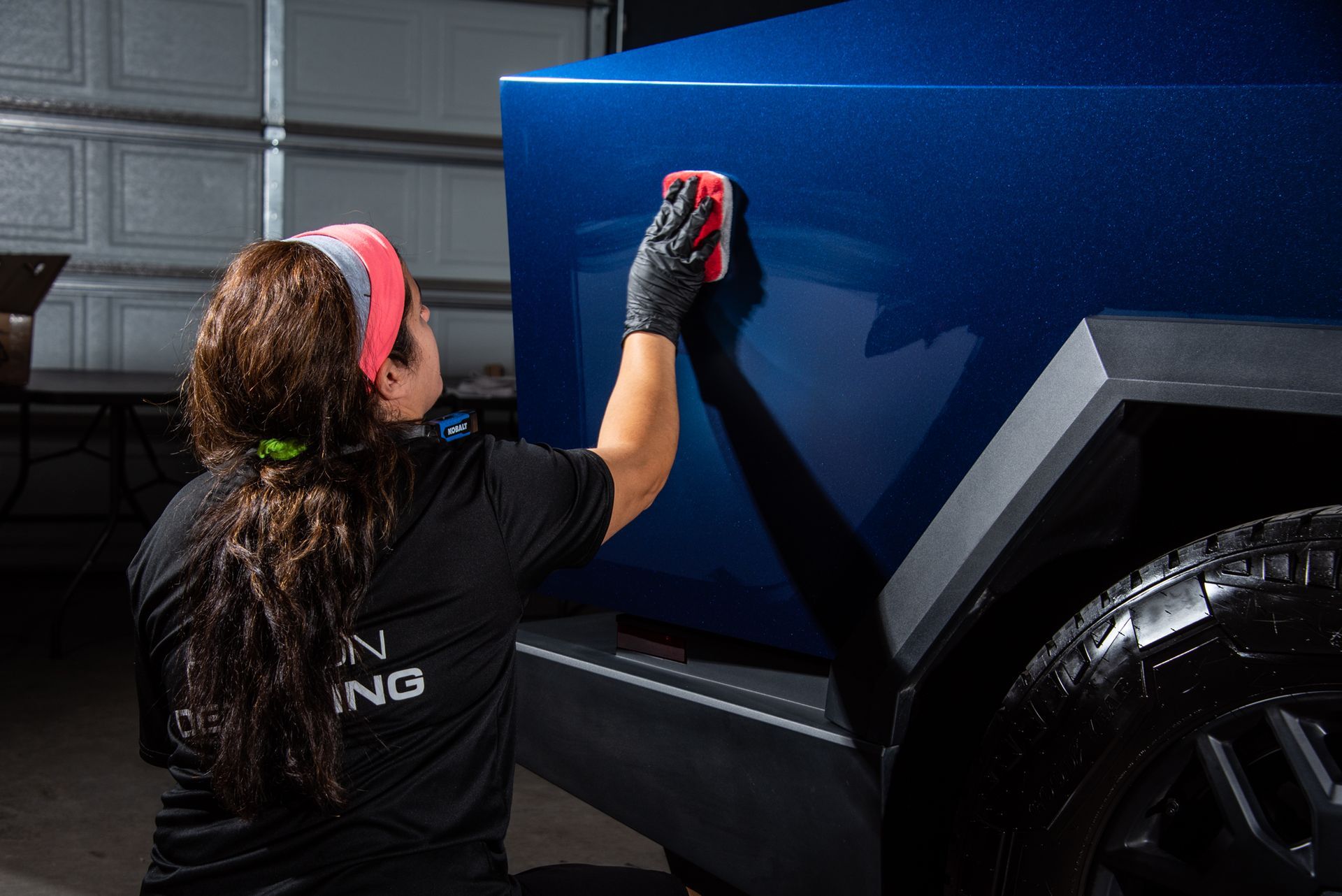 A woman applying a ceramic coating on a blue vehicle