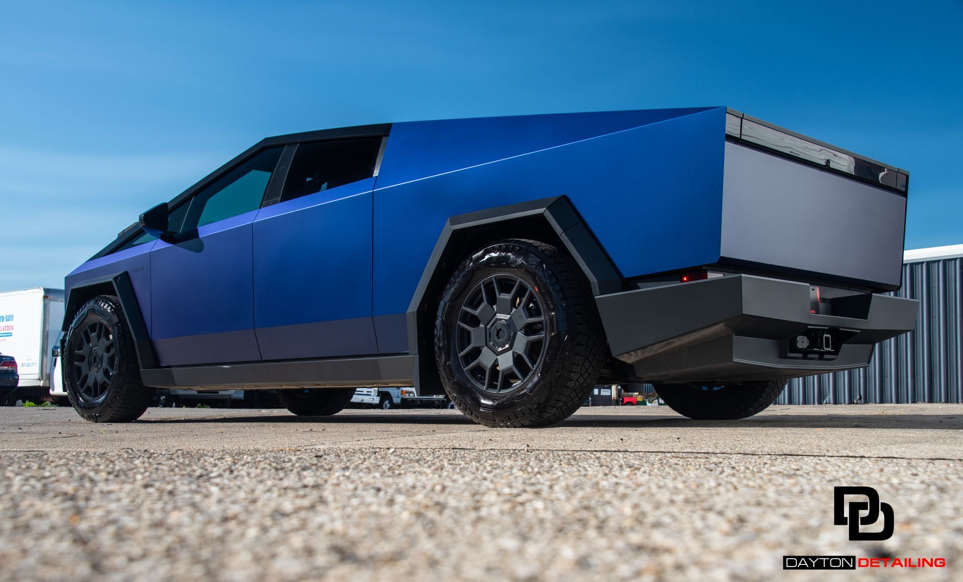 A blue tesla cybertruck is parked on the side of the road.