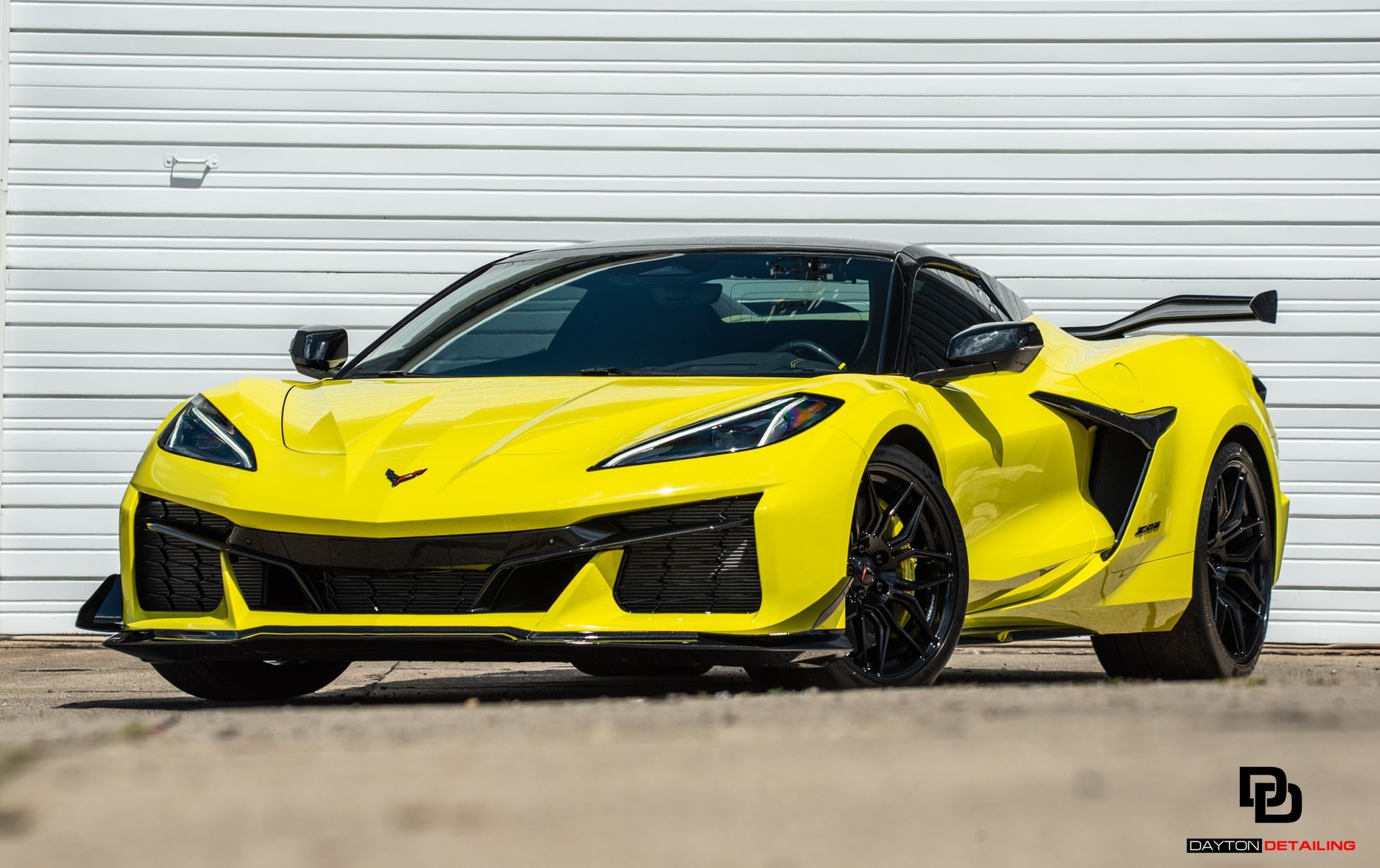 A yellow sports car is parked in front of a white wall.