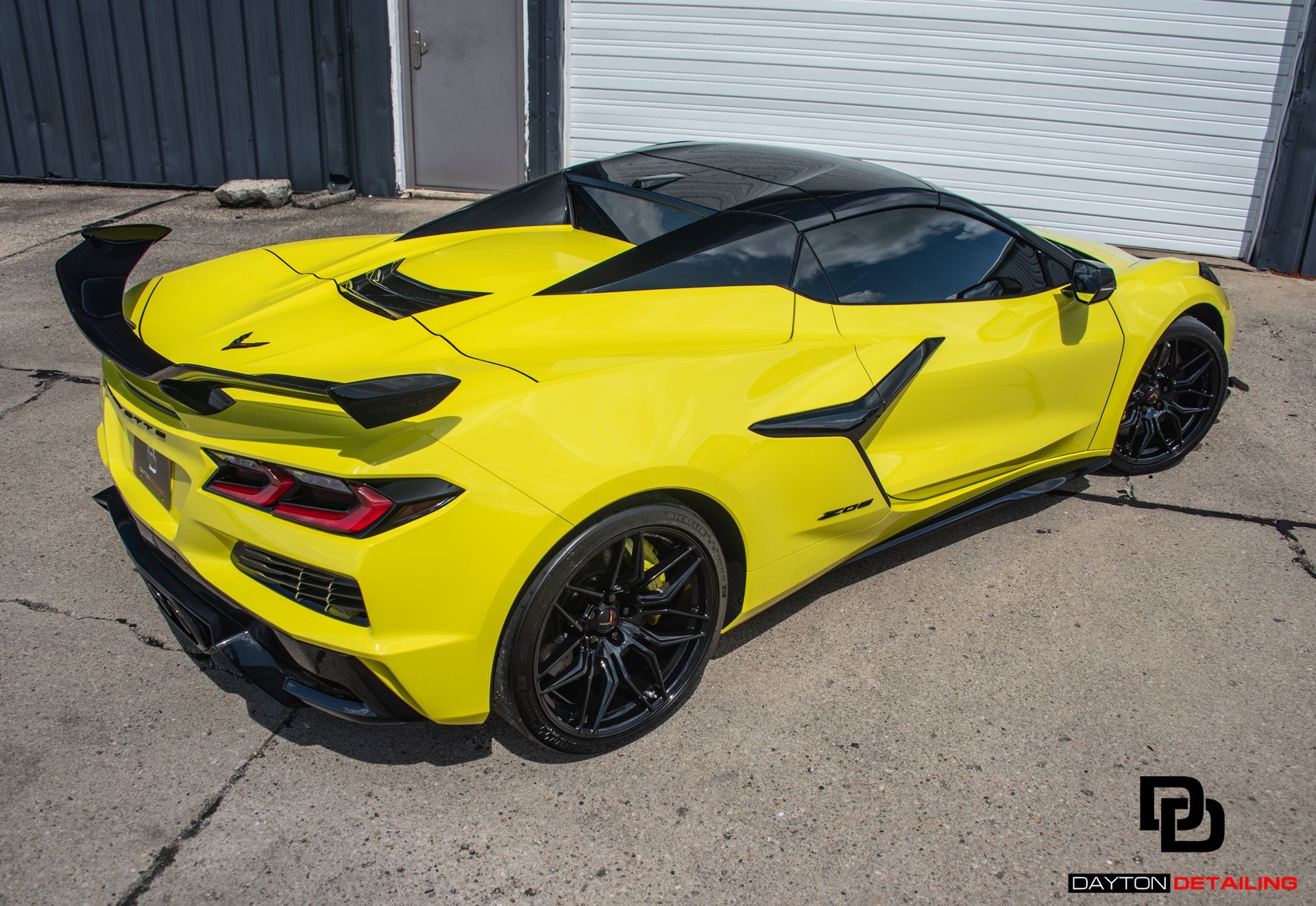 A yellow sports car is parked in front of a garage door.