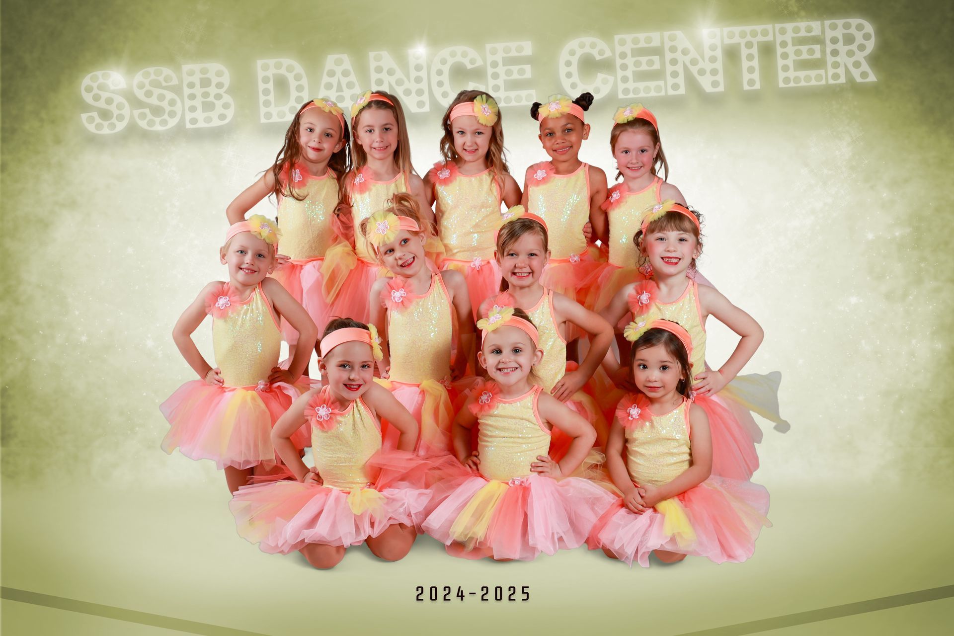 Group of young girls in yellow and pink tutus, posing for a dance center photo.