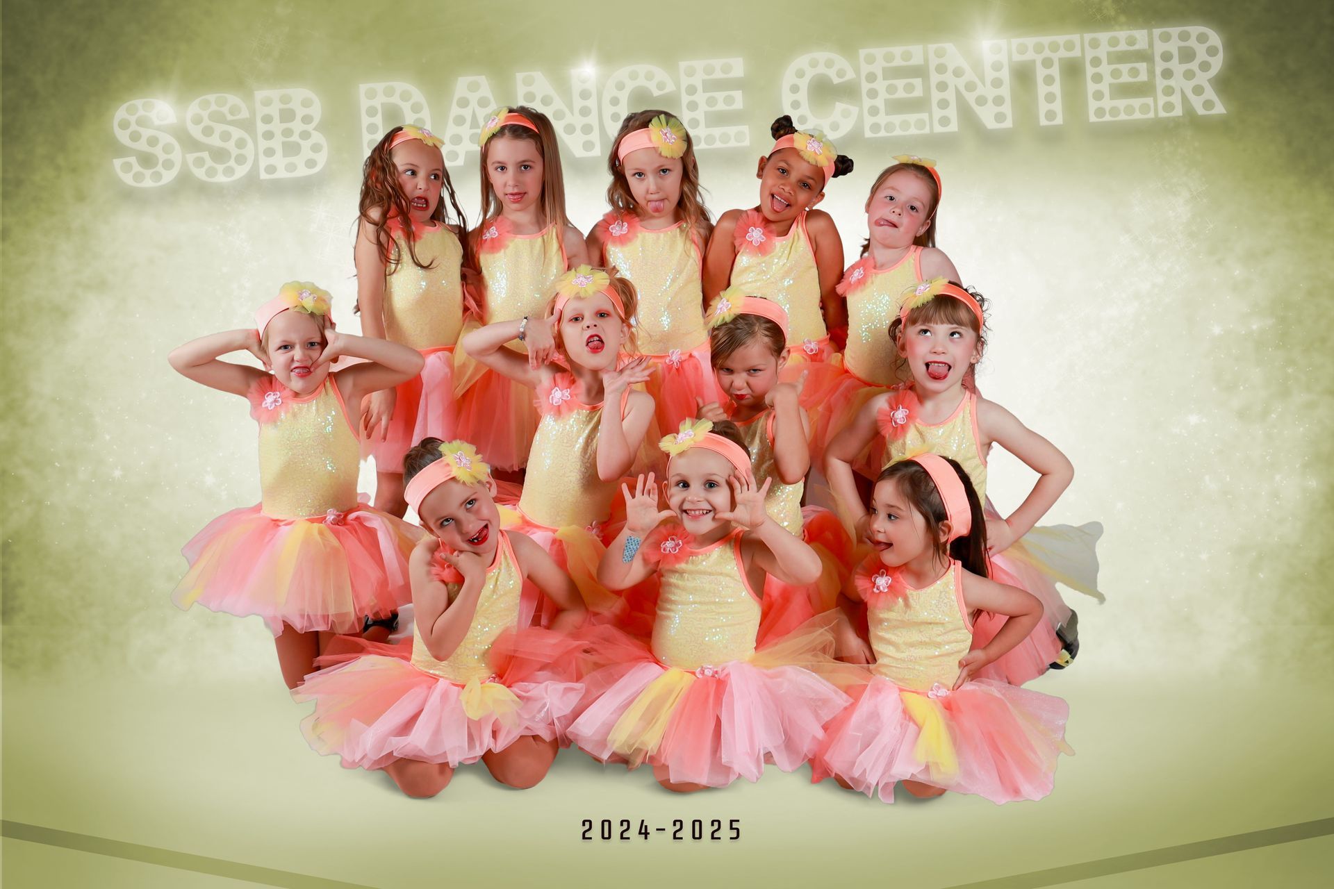 Group of young dancers in yellow and pink tutus, posing in front of 