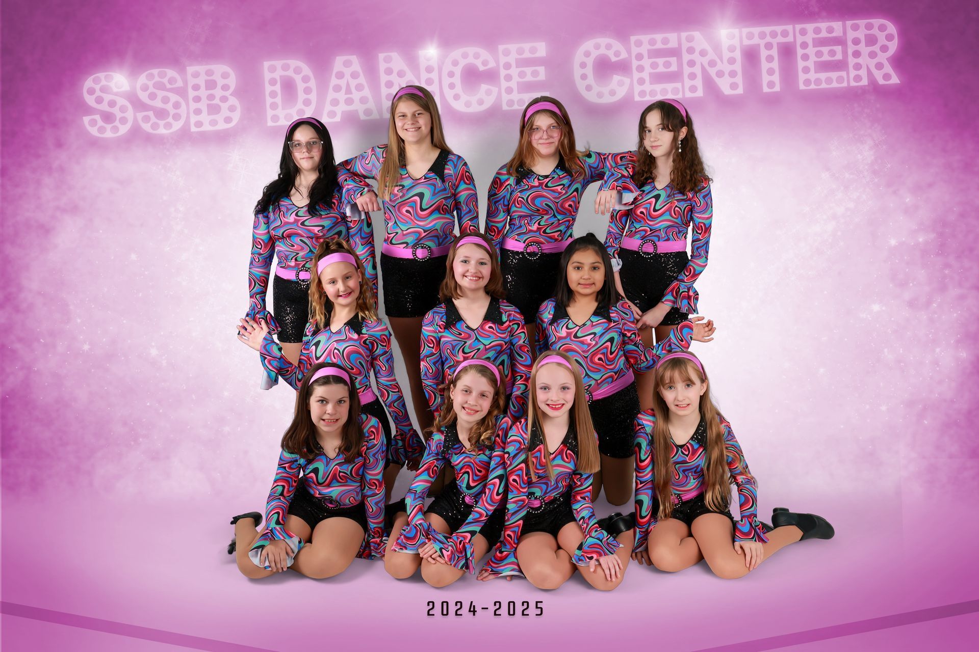 SSB Dance Center group photo of 12 dancers in matching colorful outfits on a pink background.