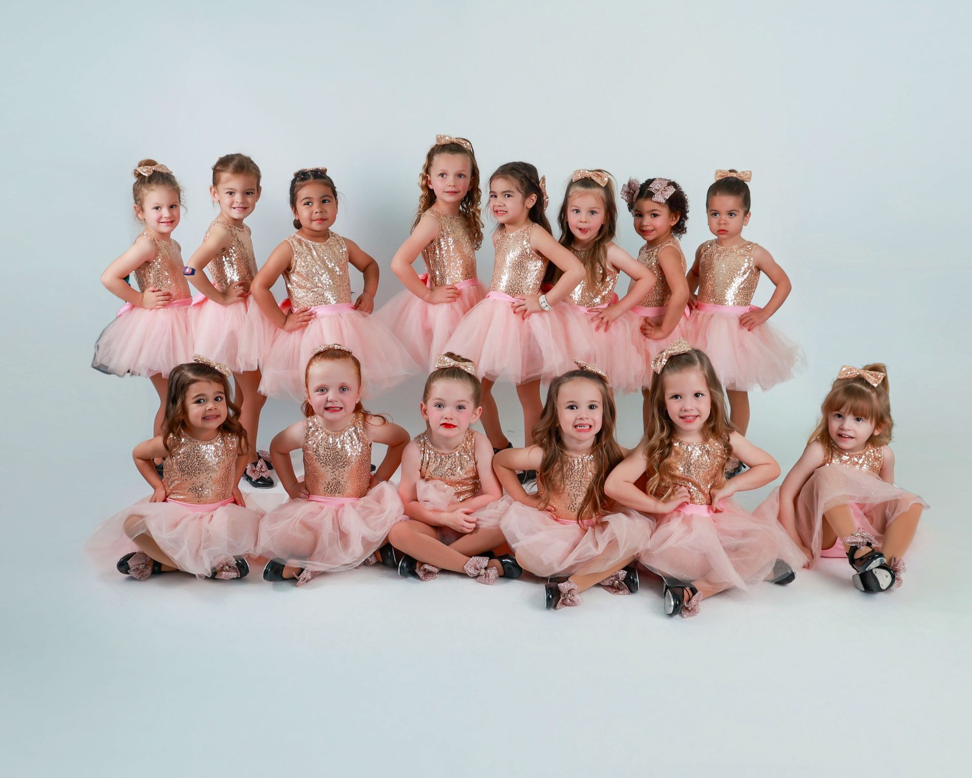 Group of young girls in pink dance outfits posing.