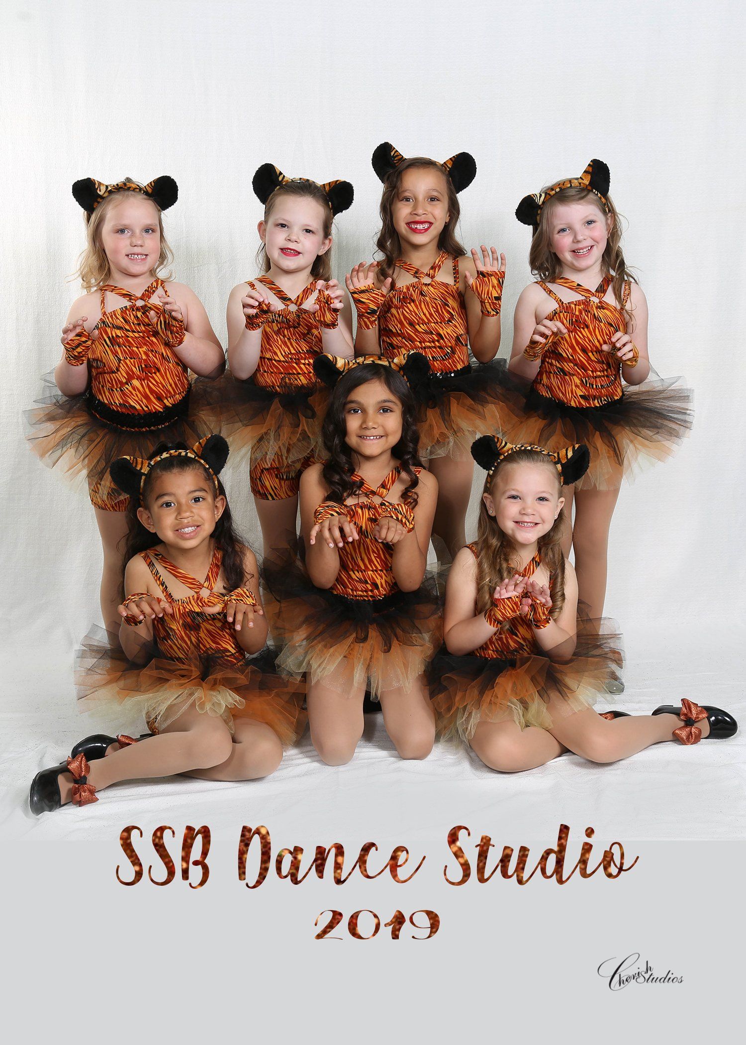 A group of young girls in tiger costumes posing for a studio portrait.
