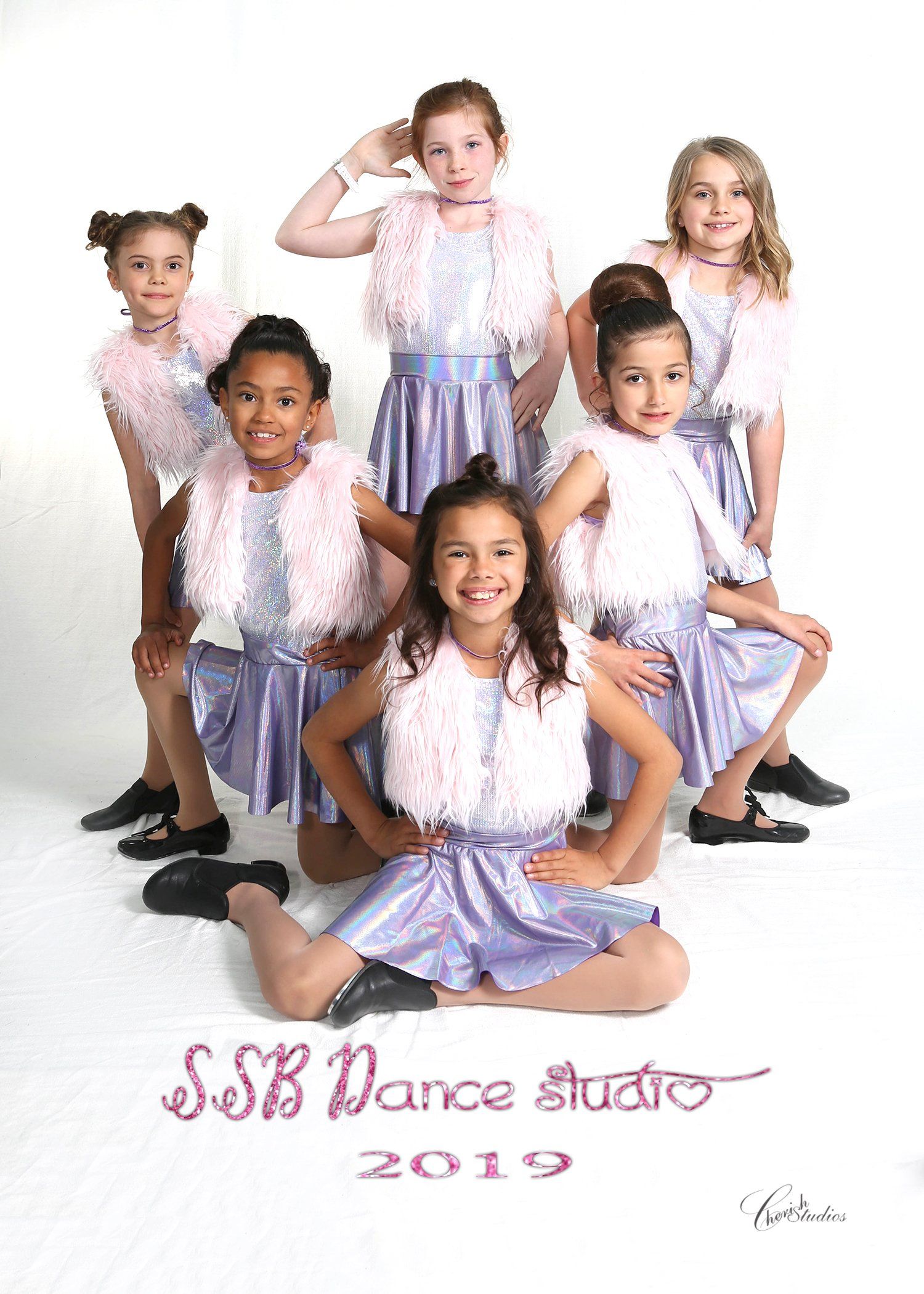 A group of young dancers in light blue outfits posing for a studio photo.