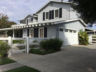 A large white house with black shutters and a white fence