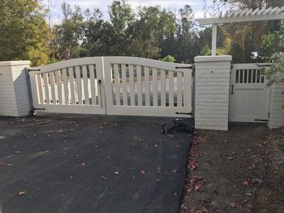 A white gate is sitting in the middle of a driveway.