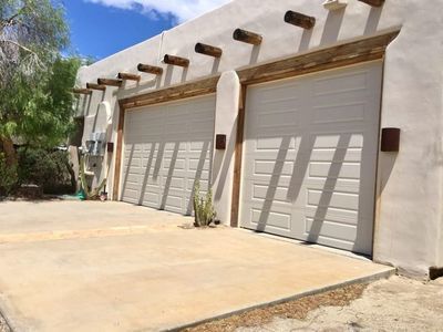 A row of white garage doors on a white building.