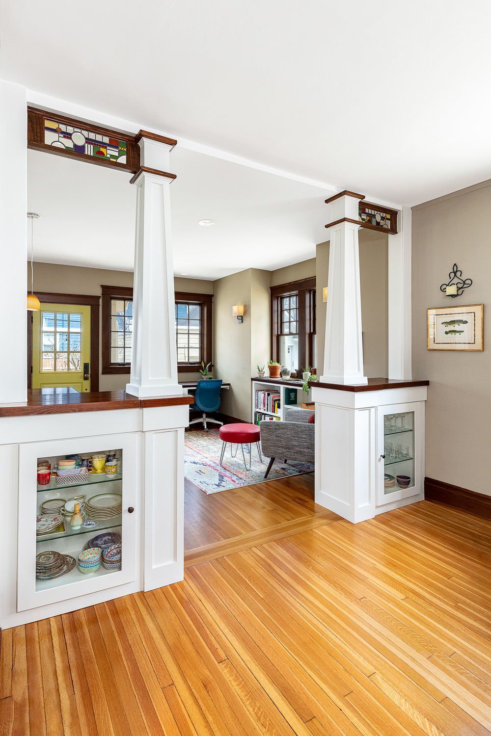 A living room with hardwood floors and a stained glass door.