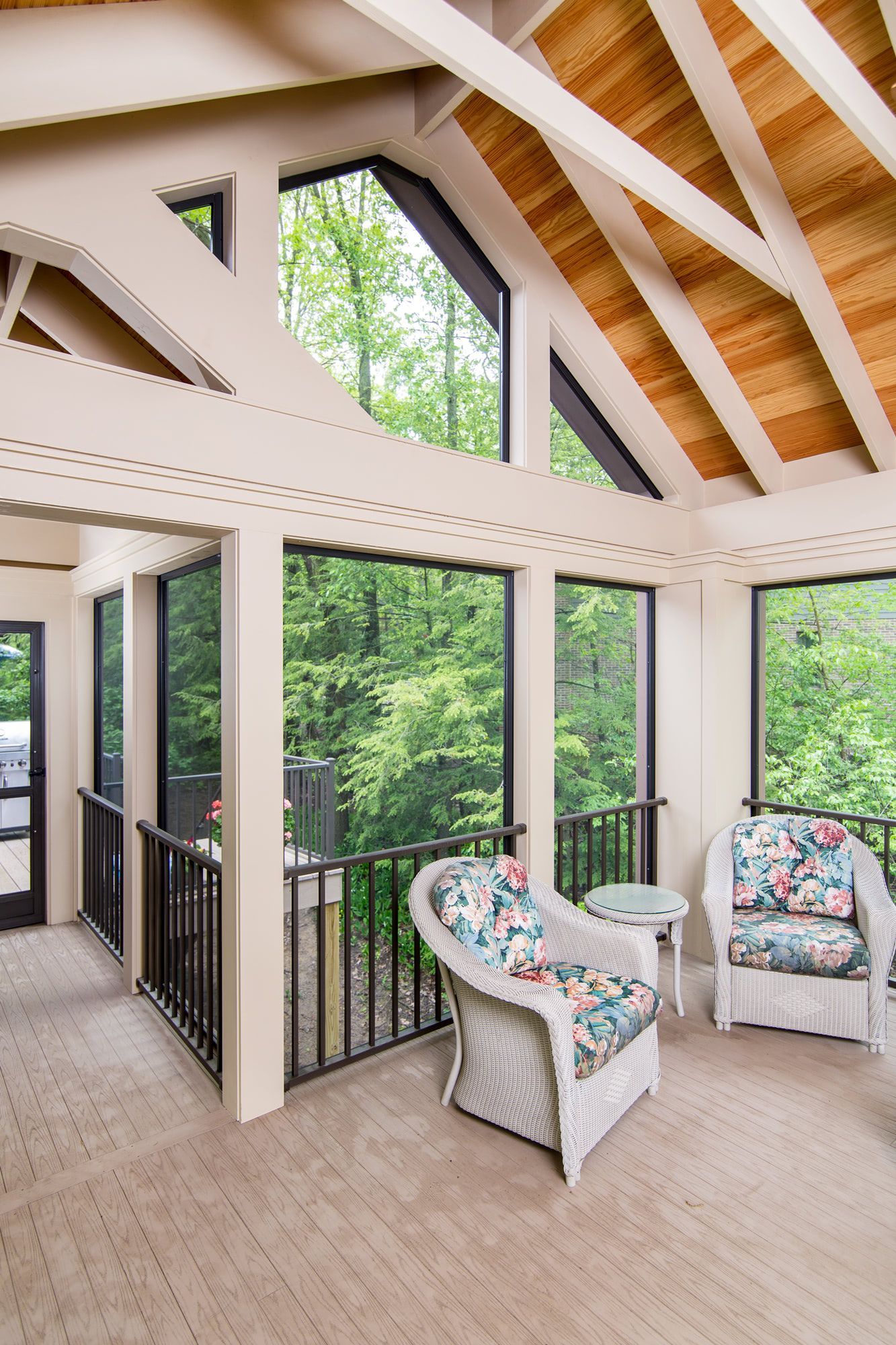 A screened in porch with chairs and a table