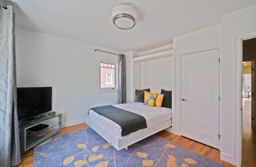 A bedroom with a bed , television , and rug.