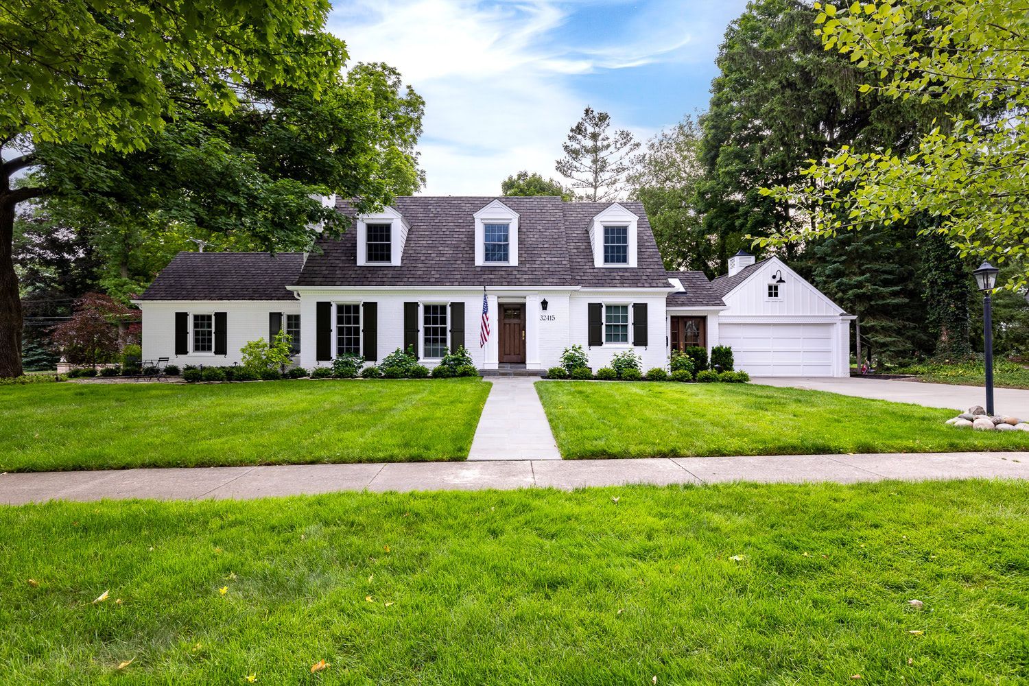 A large white house with a lush green lawn in front of it.