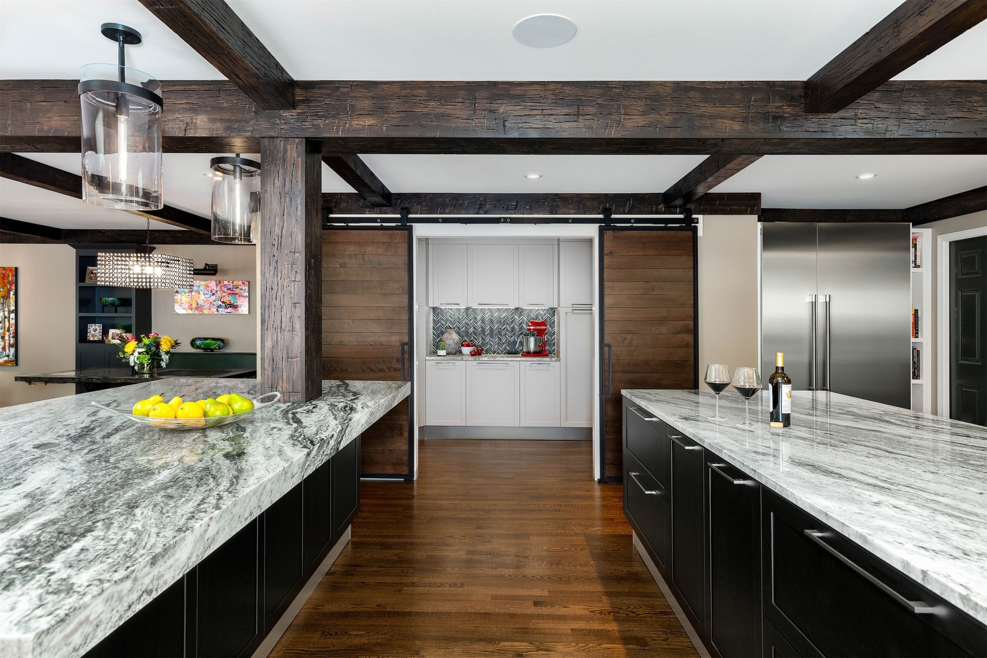 A kitchen with marble counter tops , black cabinets and stainless steel appliances.
