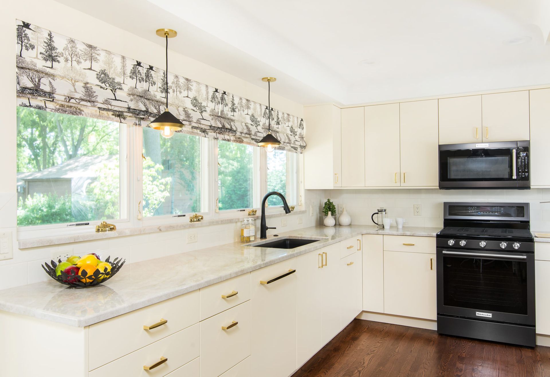 A kitchen with white cabinets , a black stove , a microwave , and a sink.