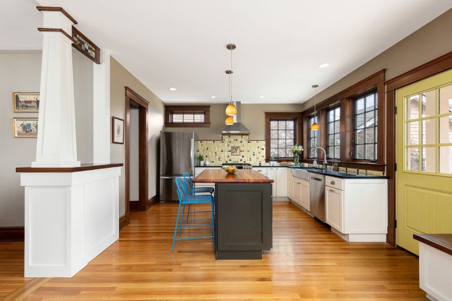 A kitchen with hardwood floors , stainless steel appliances , a large island , and a yellow door.