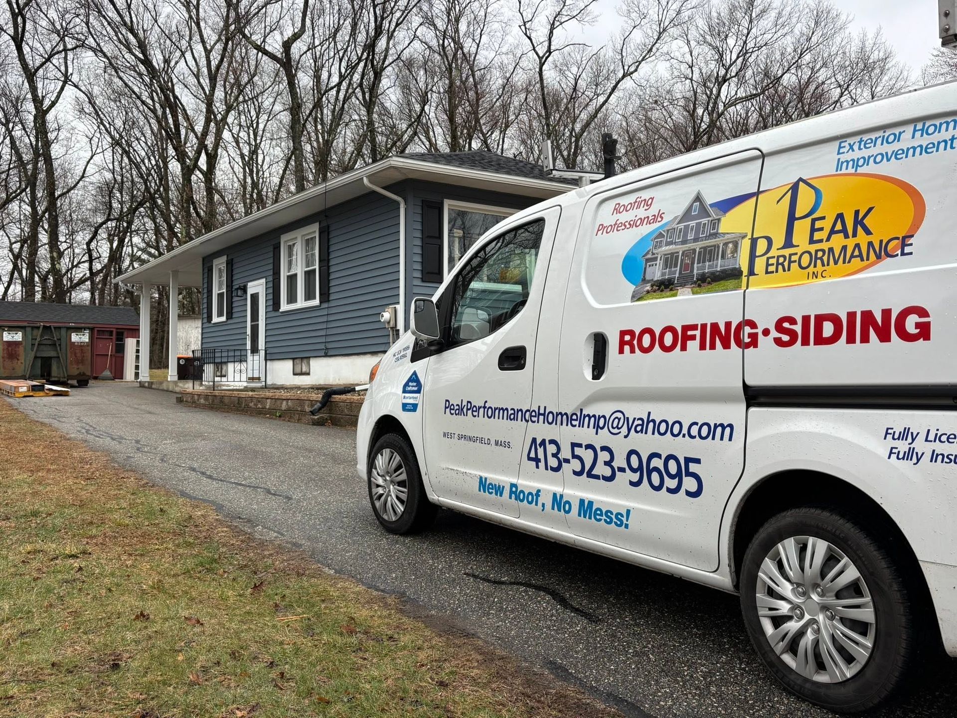 White roofing-siding van parked beside a blue house with business logos on a cloudy day White roofing-siding van parked beside a blue house with business logos on a cloudy day
