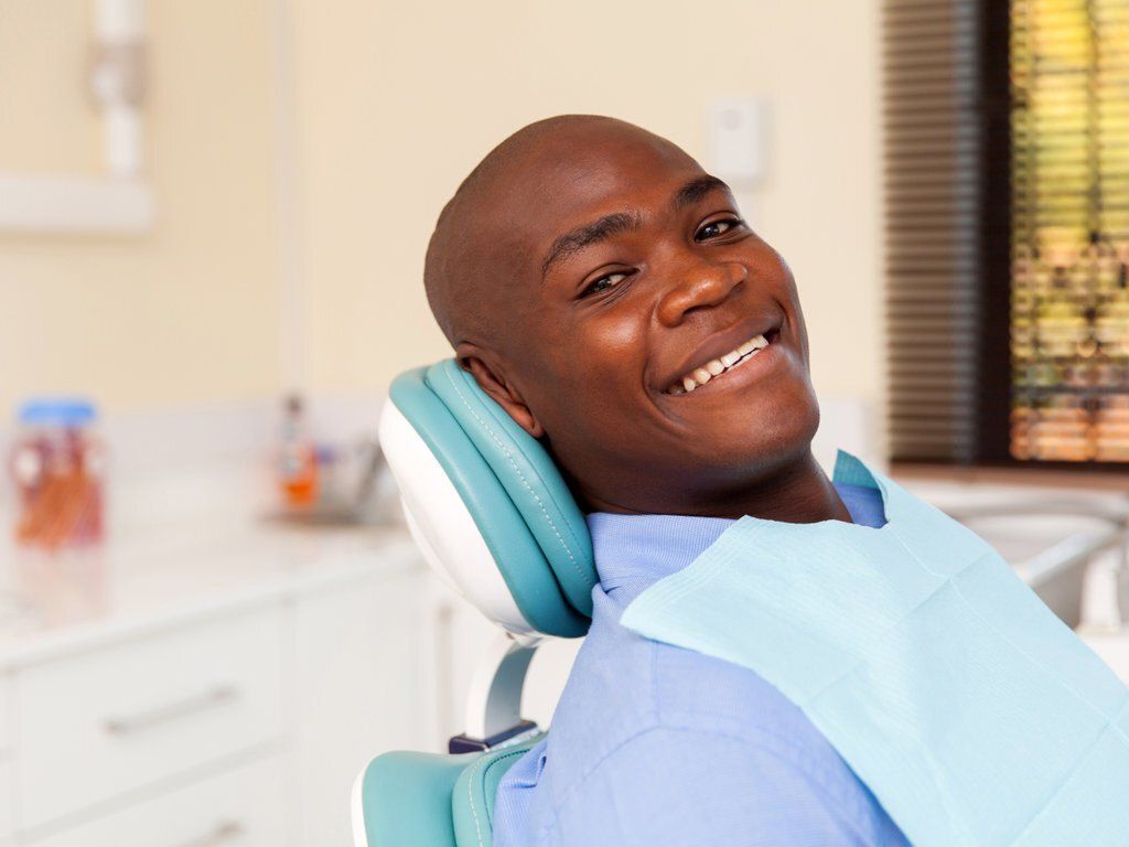 man sitting in dentist chair smiling at the camera