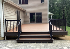 Back deck with stairs and black railings leading to a beige house patio