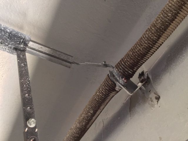 A close up of a garage door spring with a metal bracket attached to it.