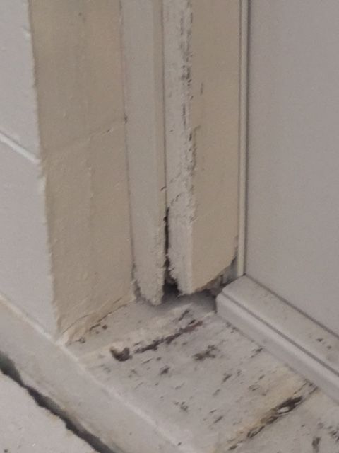 A close up of a white door with a broken frame.