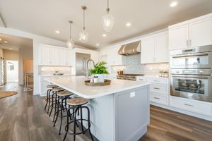 A kitchen with white cabinets , stainless steel appliances , and a large island.