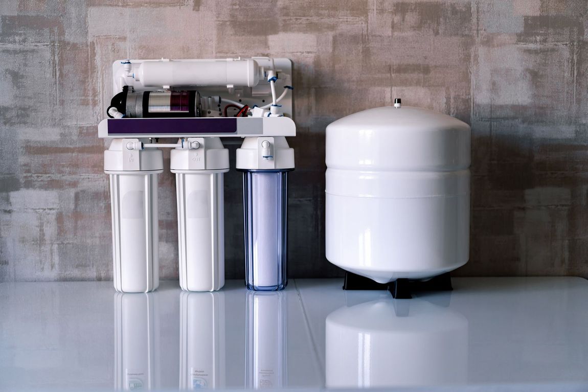 A water filter is sitting on a white counter next to a tank.