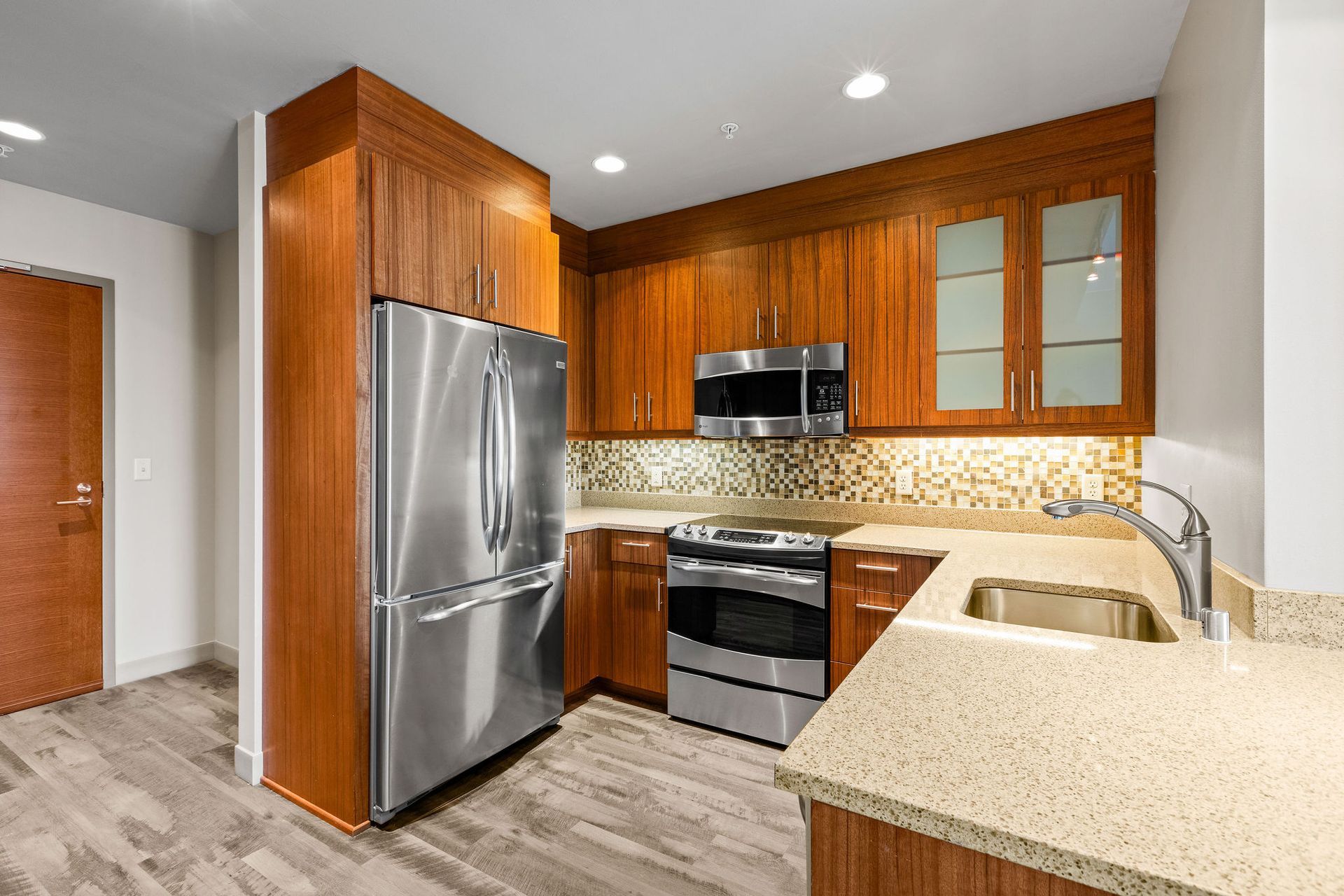 Modern kitchen with stainless steel appliances, wood cabinets, and a speckled granite countertop