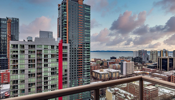 City skyline view from a balcony. Buildings with cloudy sky and water in the background.