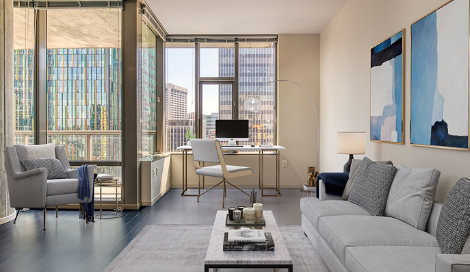 Modern living room with city view, desk, and sofa. Light walls, blue accents, large windows.